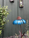 Blue Garden Petal Shape Bird Feeder in a garden next to a green fence