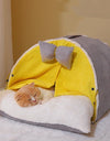 A cat sleeping in a milky yellow cozy cat cocoon 